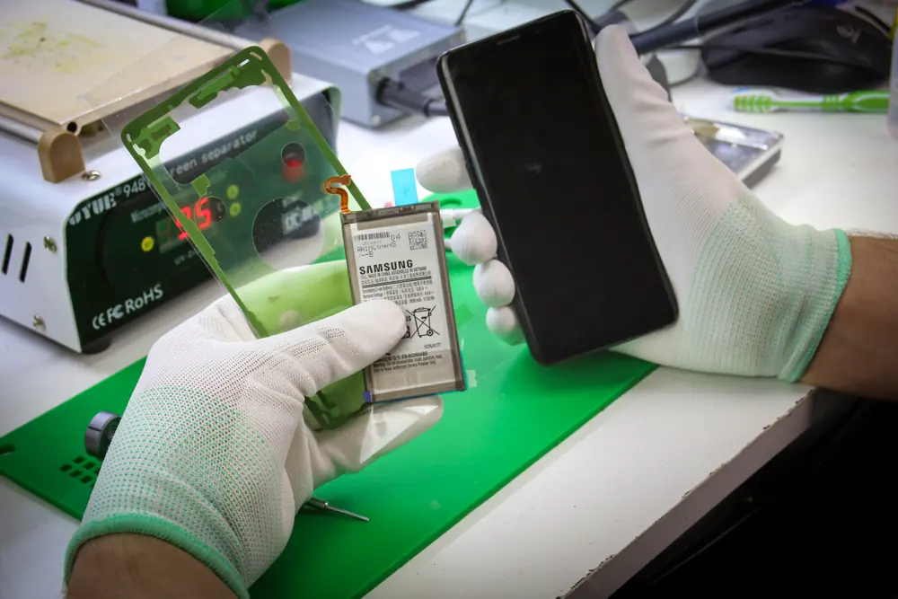 Bateria i taśma klejąca w dłoni, obok telefon