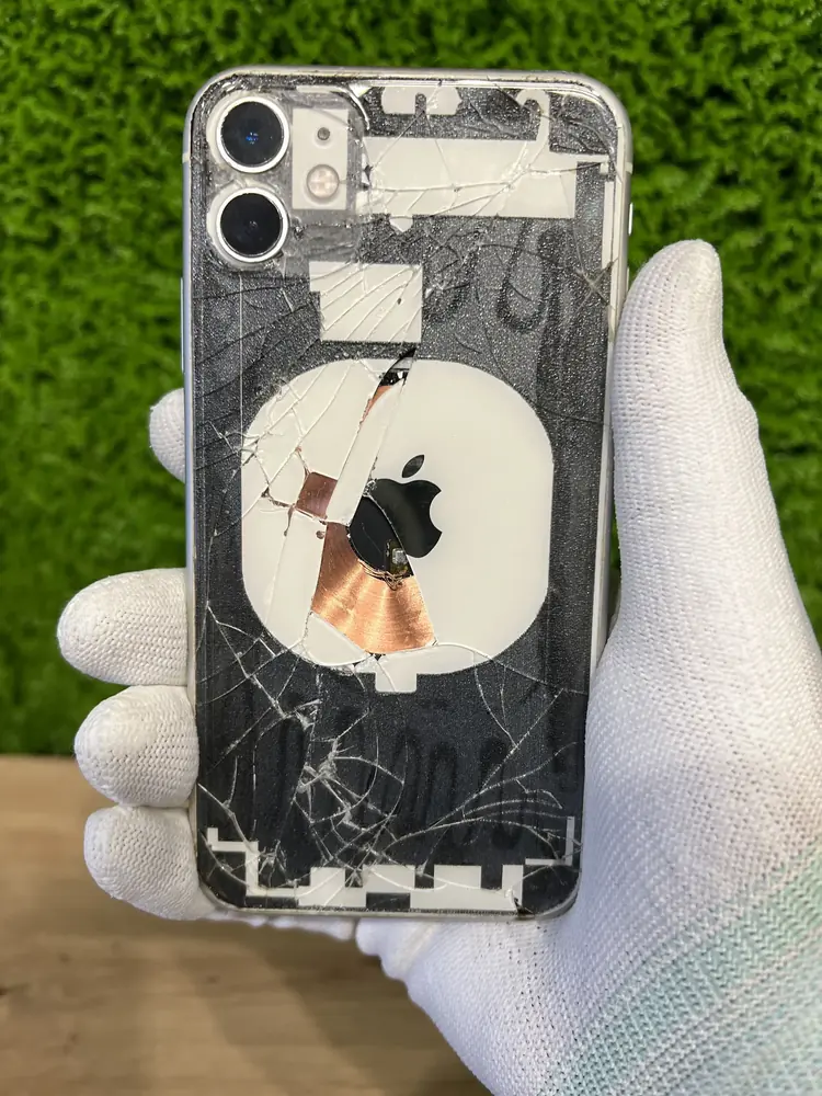 iPhone 11 w trakcie wymiany tylnej szybki — widać cewkę ładowania