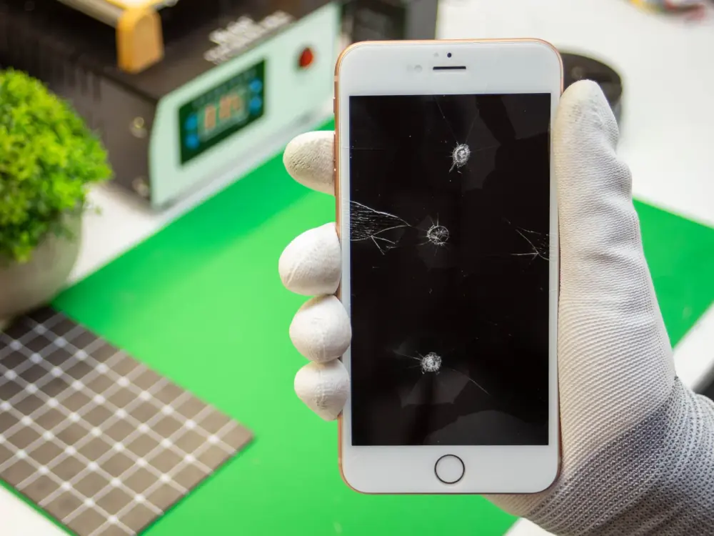 iPhone z pękniętym ekranem w dłoni na stanowisku