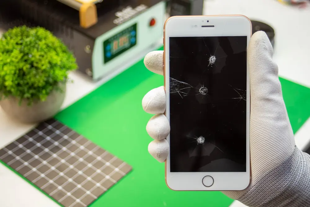 iPhone z pękniętym ekranem w dłoni