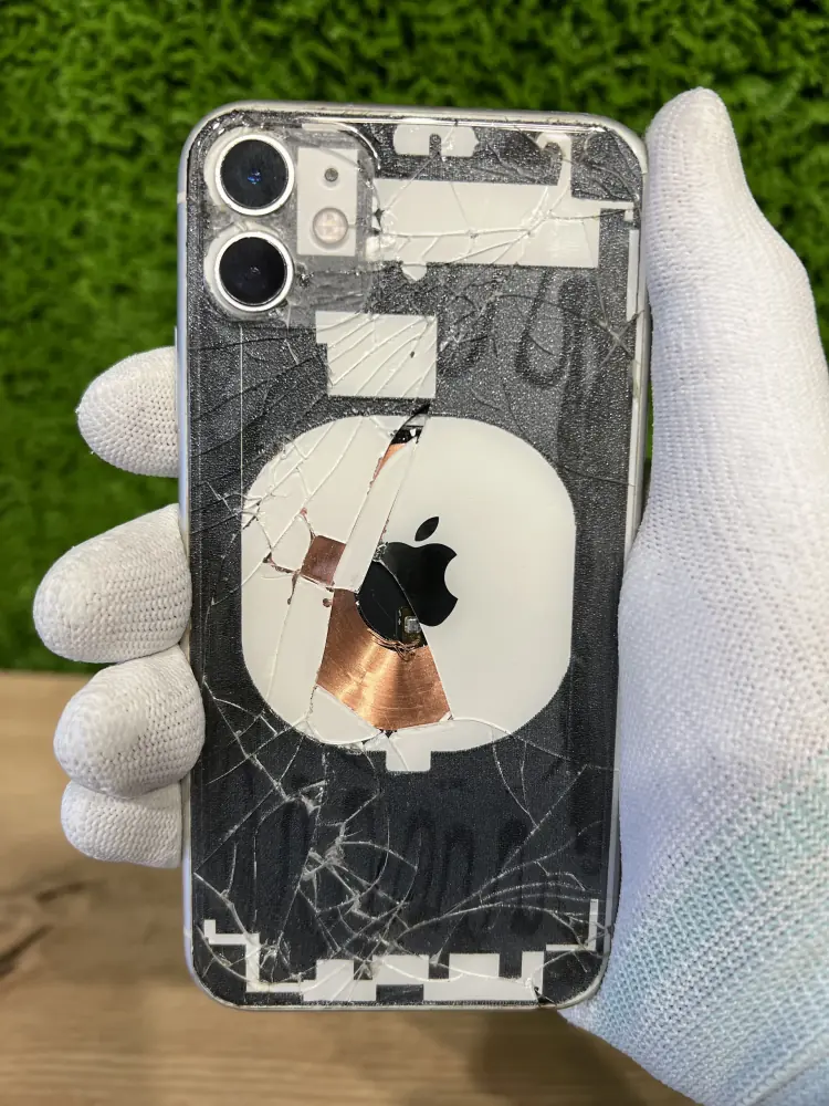 iPhone z rozbitą tylną szybą w dłoni