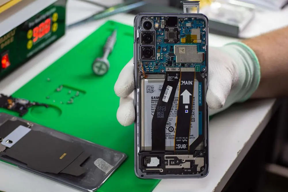 Otwarty telefon z baterią i taśmami w dłoni