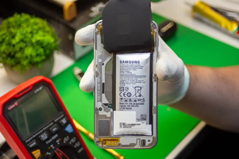 Otwarty telefon z baterią, obok multimetr