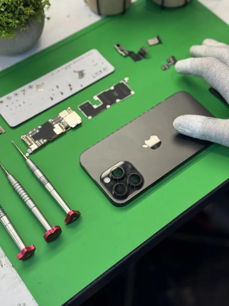 Rozłożony iPhone Pro na macie, obok wkrętaki