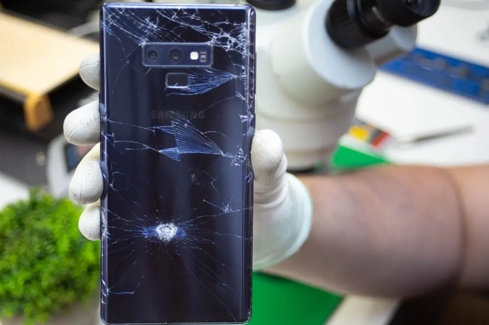 Telefon z roztrzaskaną tylną szybą w dłoni